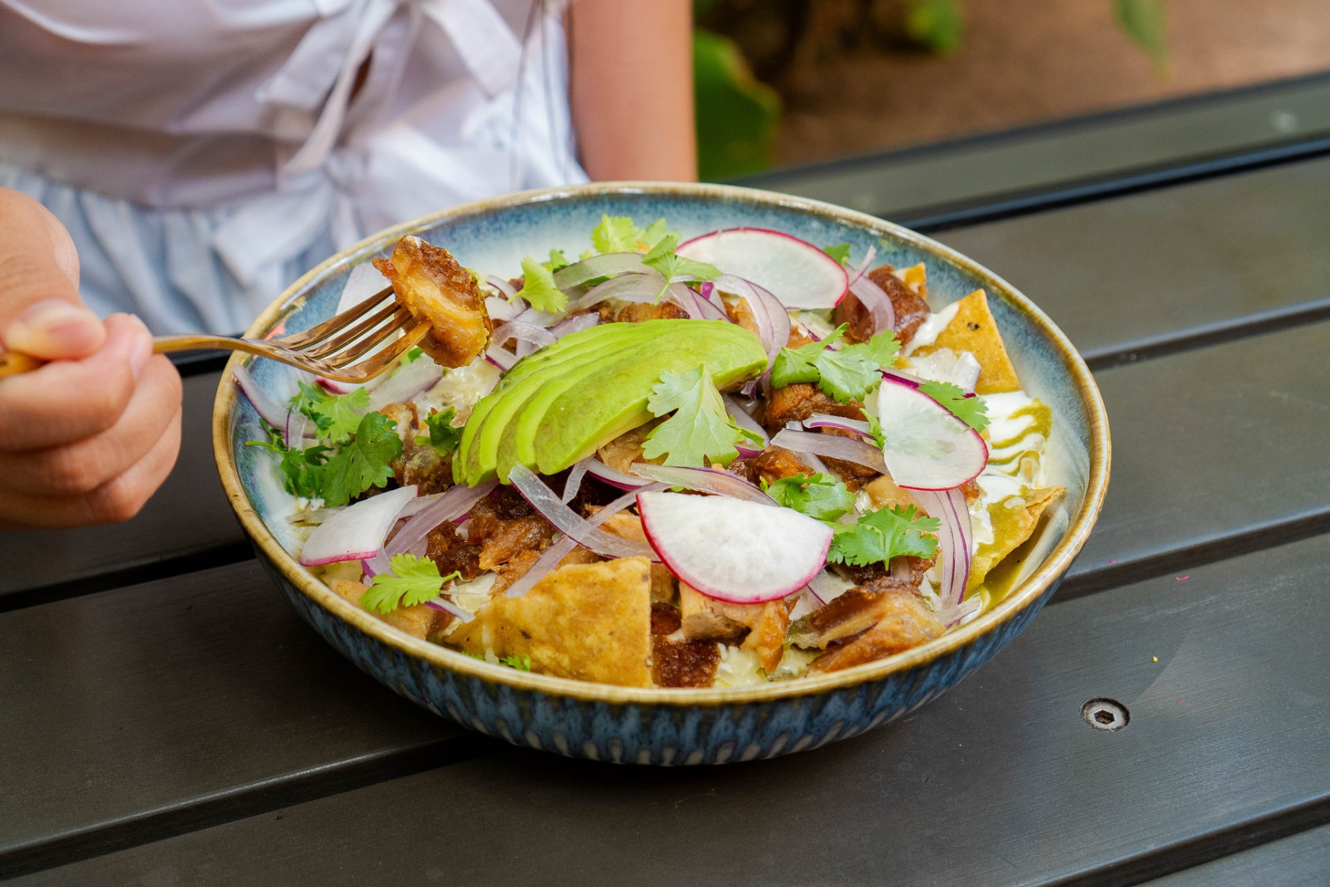 Chilaquiles verdes con castacán, aguacate, rábano y cilantro