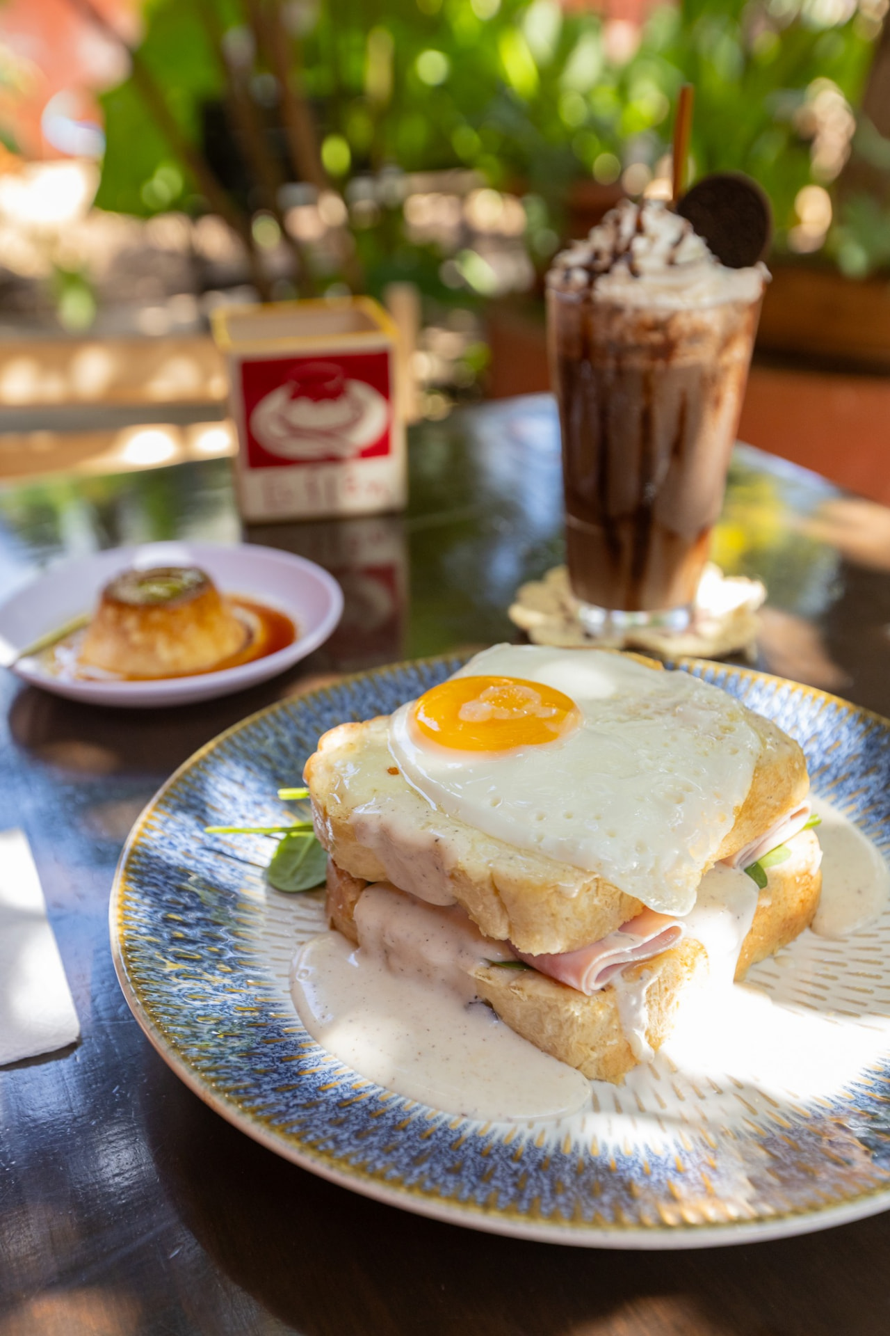 Croque madame con huevo estrellado y salsa bechamel junto a un flan